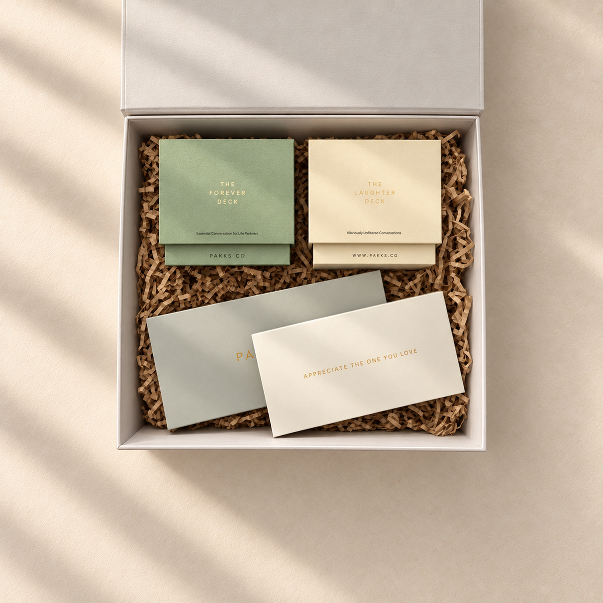 Overhead view of the open Happily Ever After Pakk in dappled light: Forever and Laughter decks, coupons and Appreciation Notes