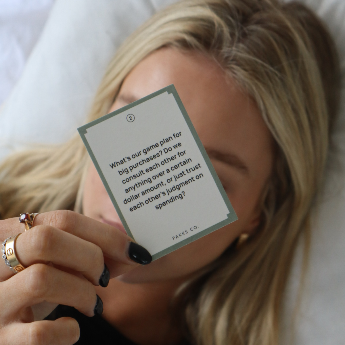 A woman lying back holding up a Forever card asking about the game plan for big purchases