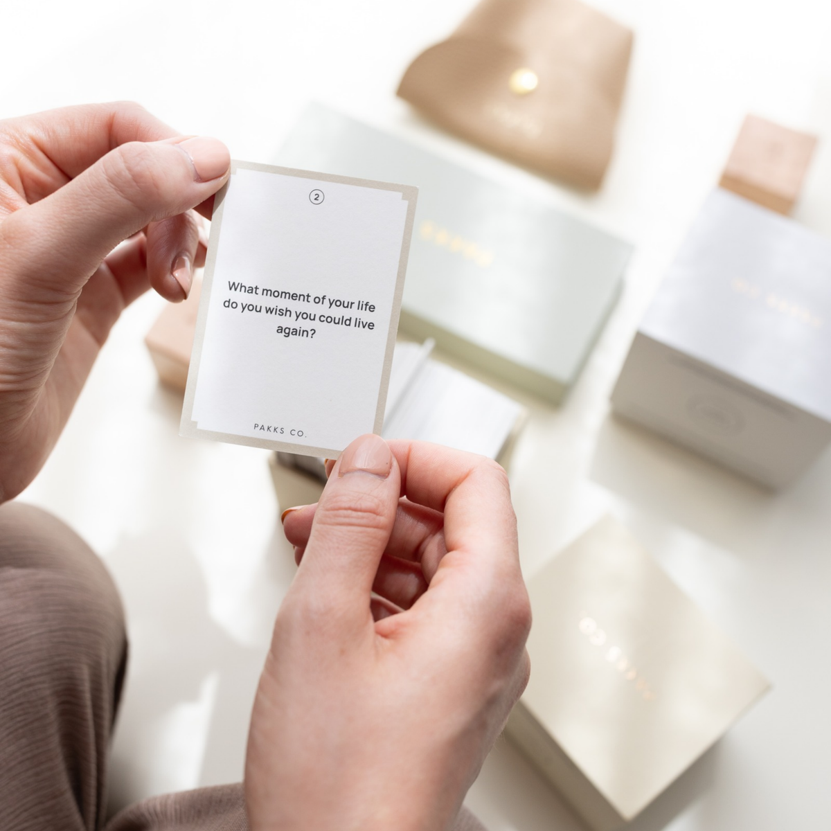 Hands holding a question card asking "What moment of your life do you wish you could live again?"