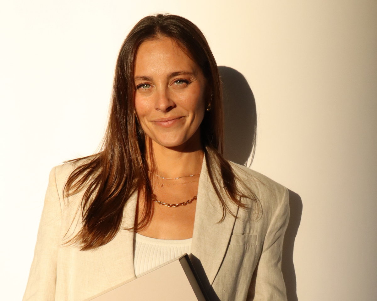 Kayci Scaggs, founder of Pakks, smiling in warm sunlight in a linen blazer